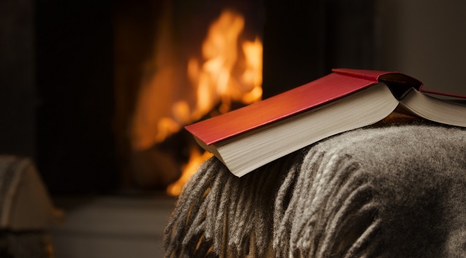 Peaceful and warm image of a open book by fireplace.